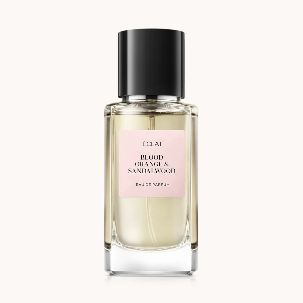 Flacon of the women’s perfume dupe ÉCLAT Blood Orange & Sandalwood, an elegant transparent glass bottle with a black cylindrical magnetic cap and a light pink label. The label displays the brand name ÉCLAT, the name Blood Orange & Sandalwood, and the phrase “Eau de Parfum”.