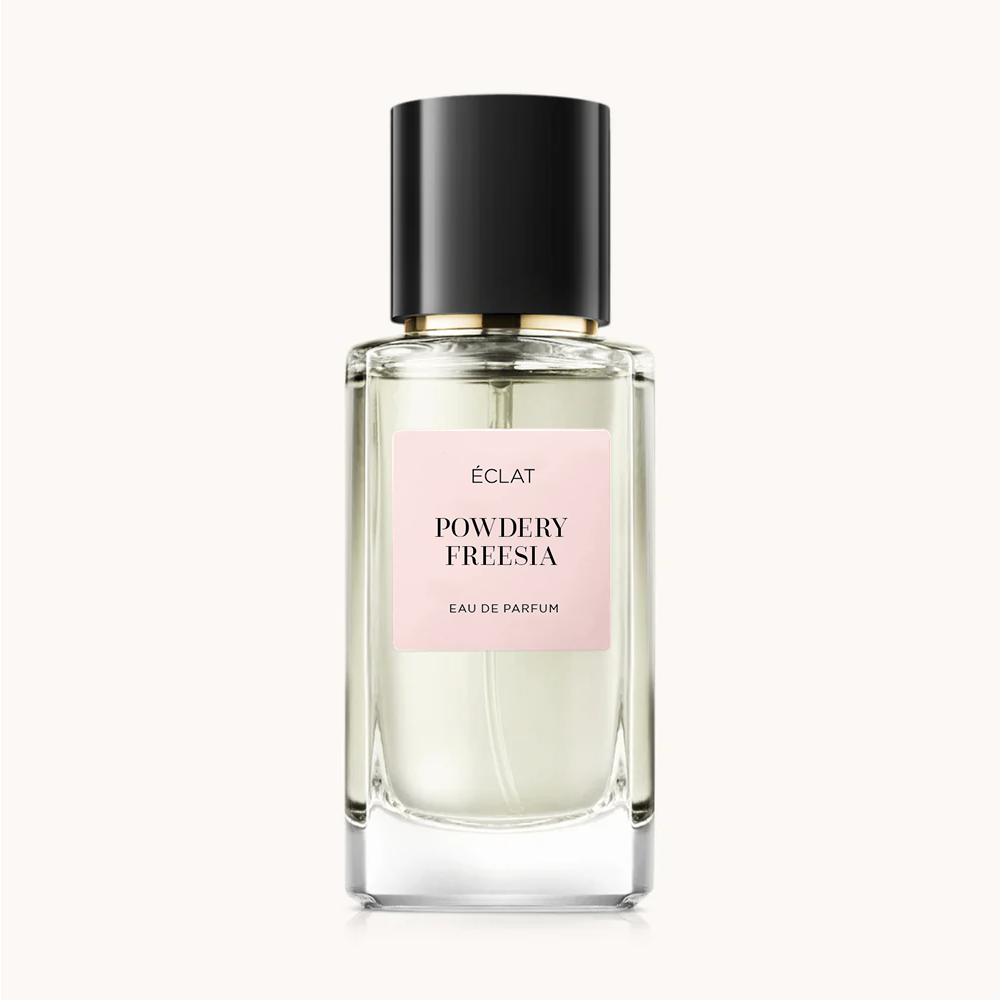 Flacon of the women’s perfume dupe ÉCLAT Powdery Freesia, an elegant transparent glass bottle with a black cylindrical magnetic cap and a light pink label. The label displays the brand name ÉCLAT, the name Powdery Freesia, and the phrase “Eau de Parfum”.