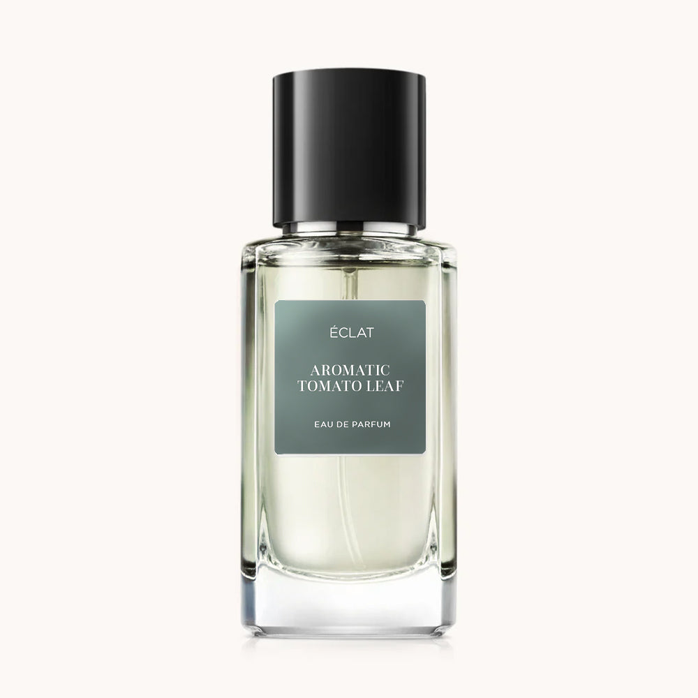 Flacon of the men's perfume dupe ÉCLAT Aromatic Tomato Leaf, an elegant transparent glass bottle with a black cylindrical magnetic cap and a green label. The label displays the brand name ÉCLAT, the name Aromatic Tomato Leaf, and the phrase “Eau de Parfum”.