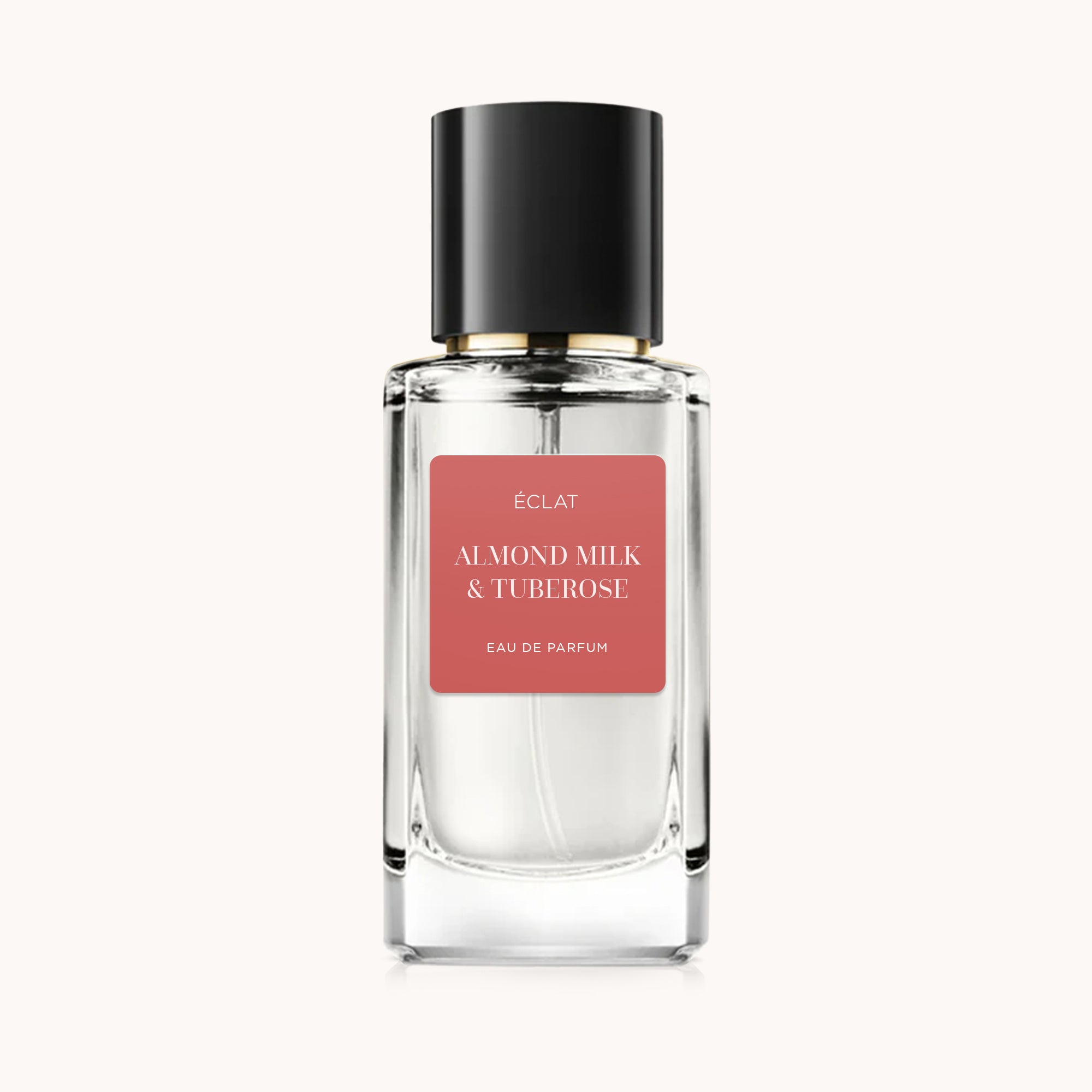 Flacone in vetro trasparente di ÉCLAT Almond Milk & Tuberose con tappo nero ed etichetta rosa.