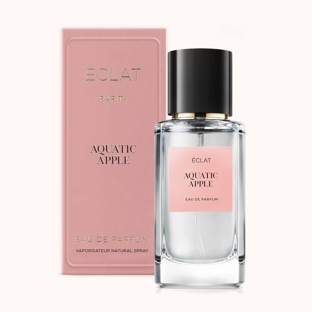 Un flacone di vetro sfaccettato di ÉCLAT Aquatic Apple con tappo nero, accompagnato da una scatola rosa con elegante marchio.
