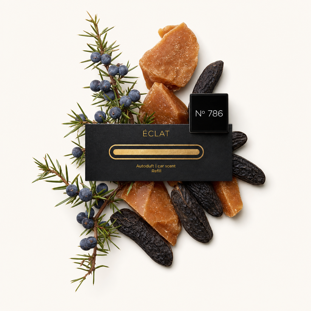 Un arrangiamento di pezzi di resina marrone, fave di tonka essiccate e bacche di ginepro circonda un tappo nero con etichetta dorata ÉCLAT.