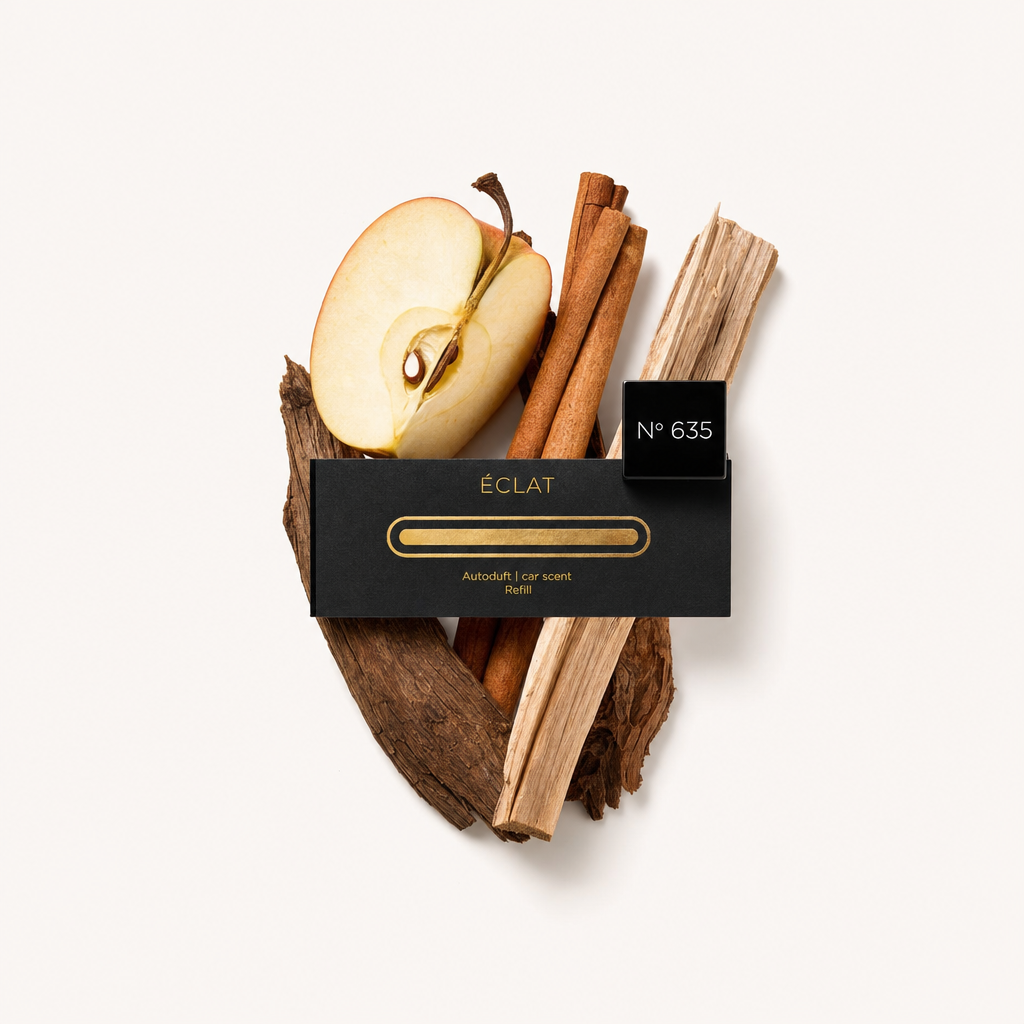 Un arrangiamento di natura morta con fettina di mela, bastoncini di cannella e pezzi di legno, con il tappo nero ÉCLAT etichettato "N° 635" sopra.