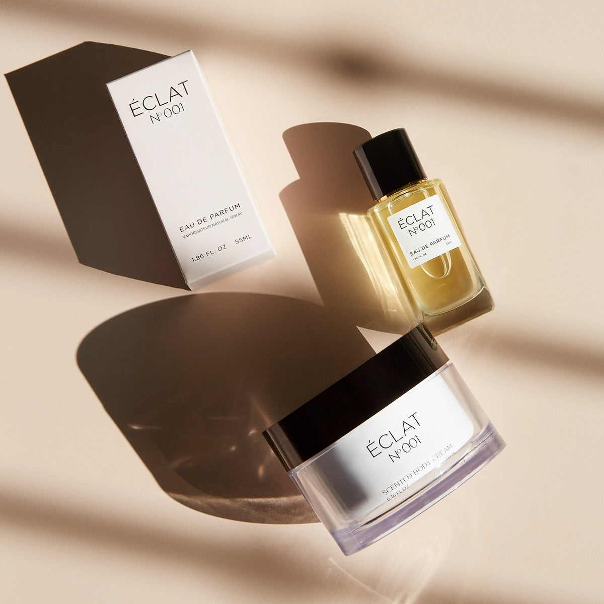 Profumo ÉCLAT Floral Aldehydes e crema corpo profumata con tappo nero accanto a una scatola bianca su una superficie chiara.