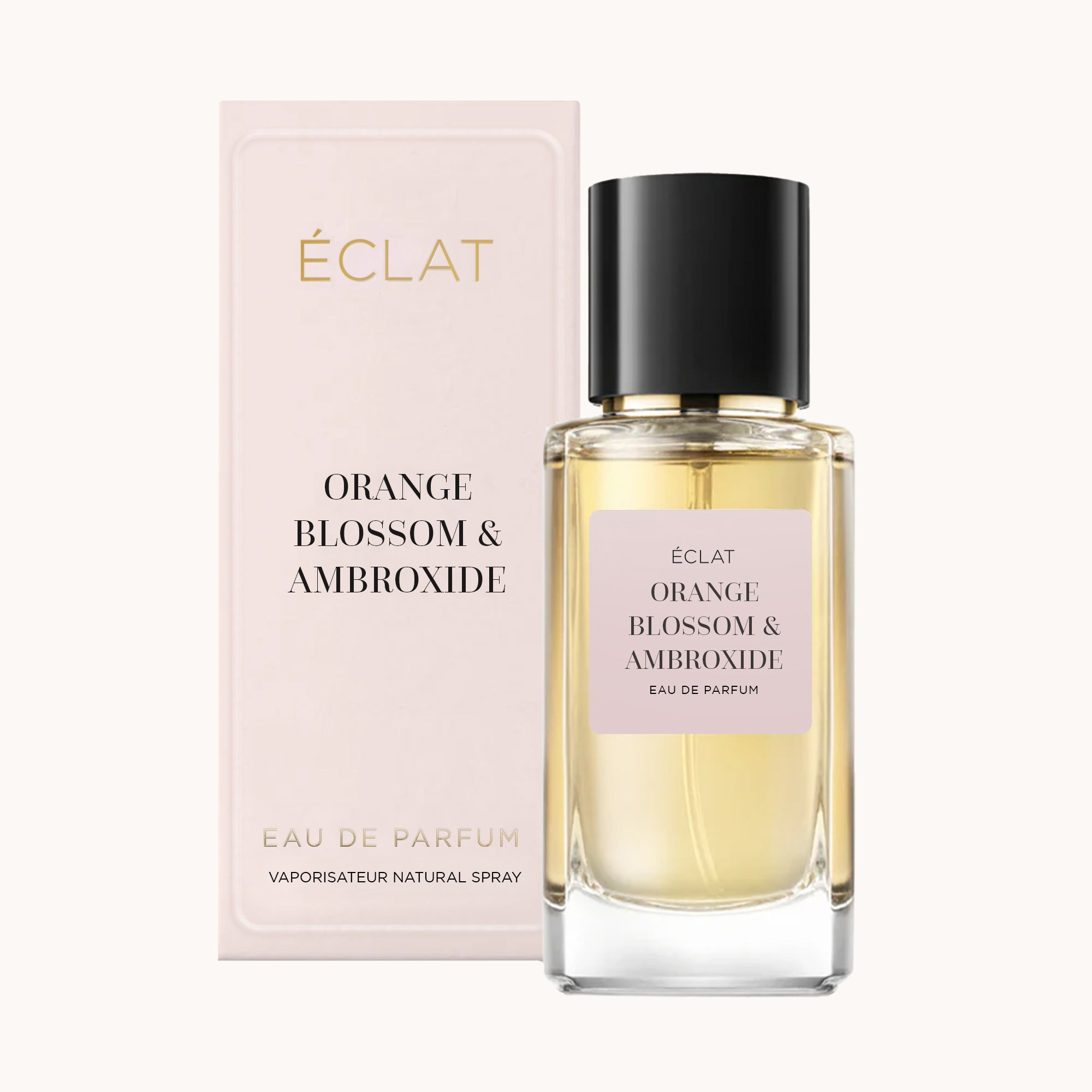 Elegante profumo ÉCLAT Orange Blossom & Ambroxide con flacone in vetro sfaccettato e tappo nero, accompagnato da una scatola rosa pastello.