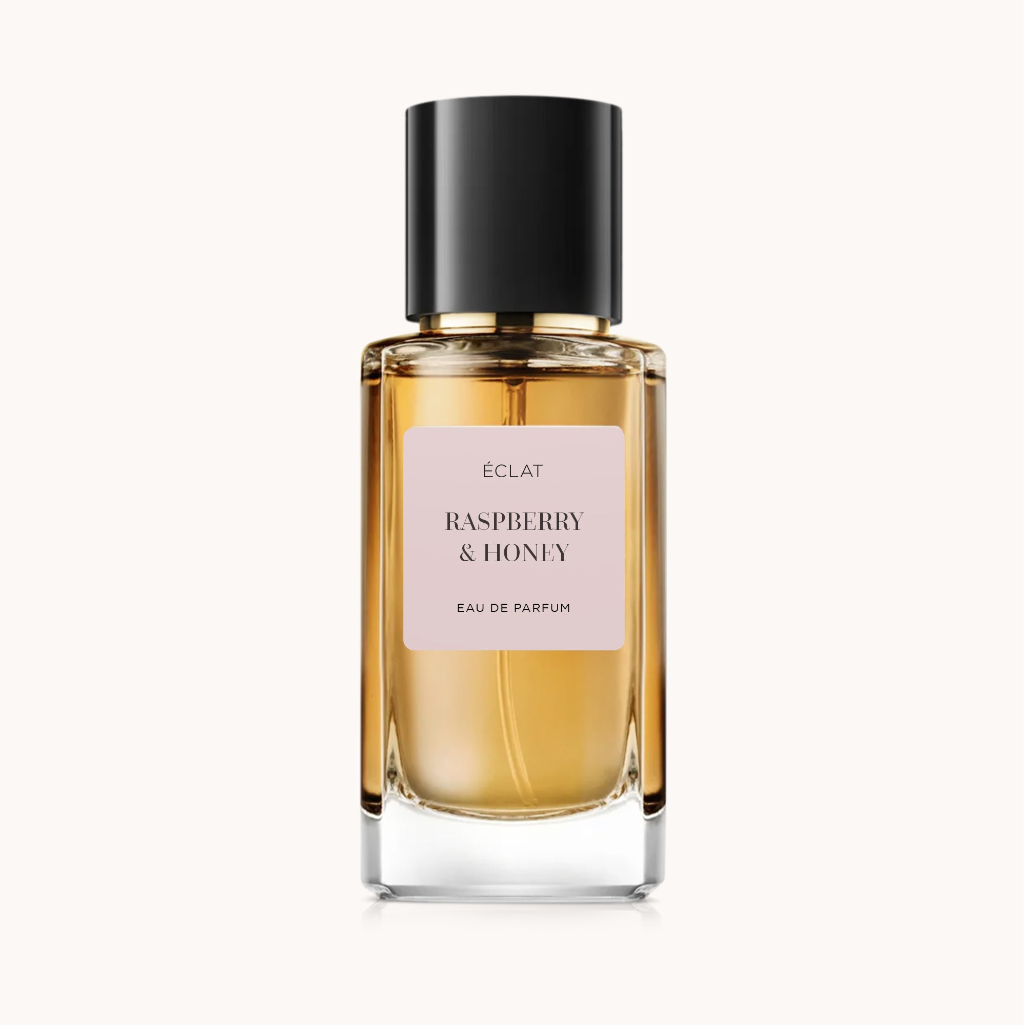 Una bottiglia di vetro sfaccettata del profumo ÉCLAT Raspberry & Honey con etichetta opaca e tappo nero.