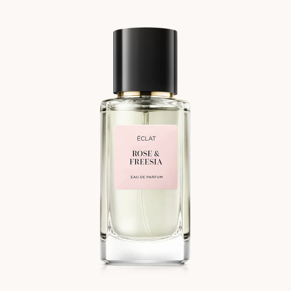 Bottiglia in vetro sfaccettato con etichetta ÉCLAT Rose & Freesia, tappo nero e etichetta rosa tenue.