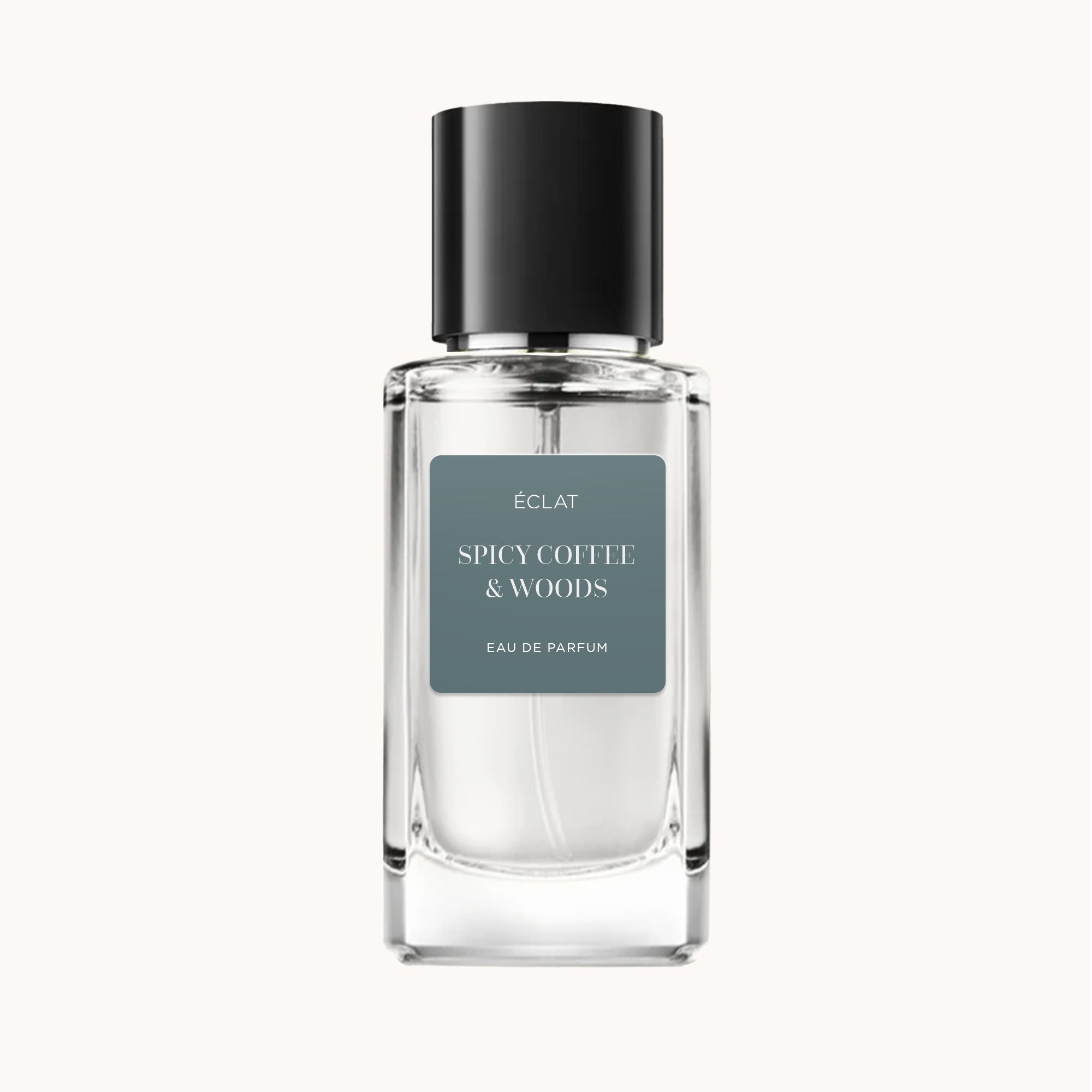 Il flacone del profumo ÉCLAT Spicy Coffee & Woods presenta un vetro sfaccettato trasparente con tappo nero e etichetta grigia opaca.