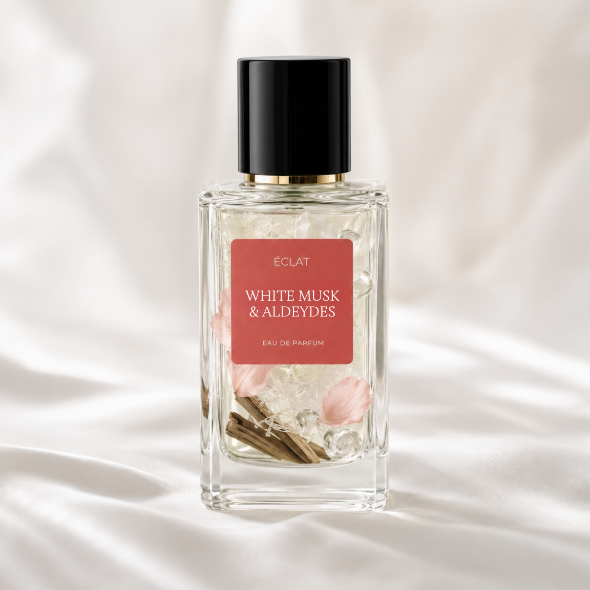 ÉCLAT White Musk & Aldehydes in un flacone di vetro sfaccettato con tappo nero e etichetta rossa su uno sfondo di tessuto bianco morbido.
