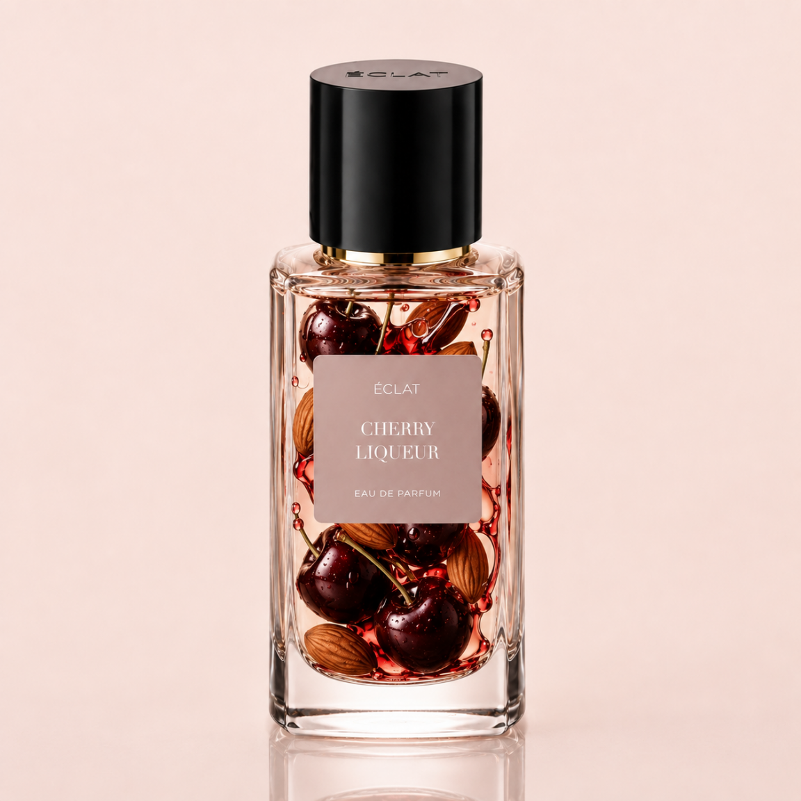 Boccetta in vetro sfaccettato di ÉCLAT Cherry Liqueur eau de parfum con tappo nero e etichetta che raffigura ciliegie e mandorle.