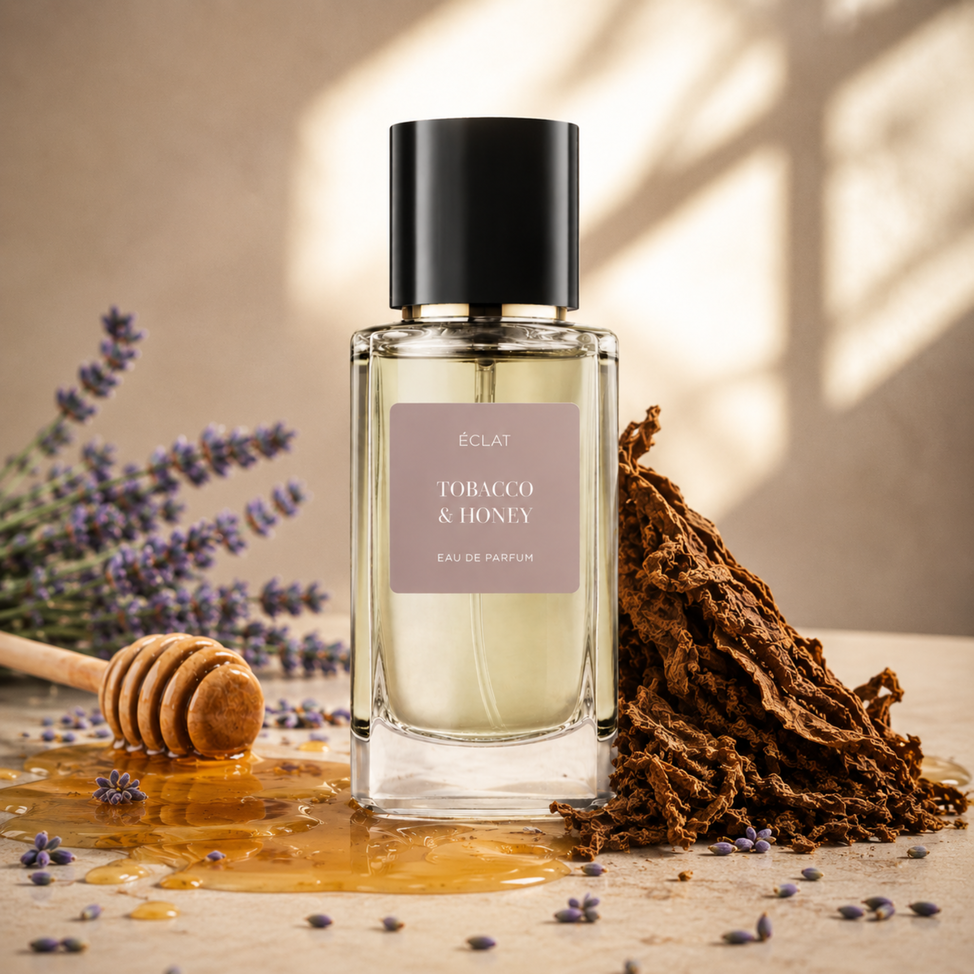 Un flacone in vetro sfaccettato di ÉCLAT Tobacco & Honey con tappo nero, circondato da miele, foglie di tabacco e rametti di lavanda.