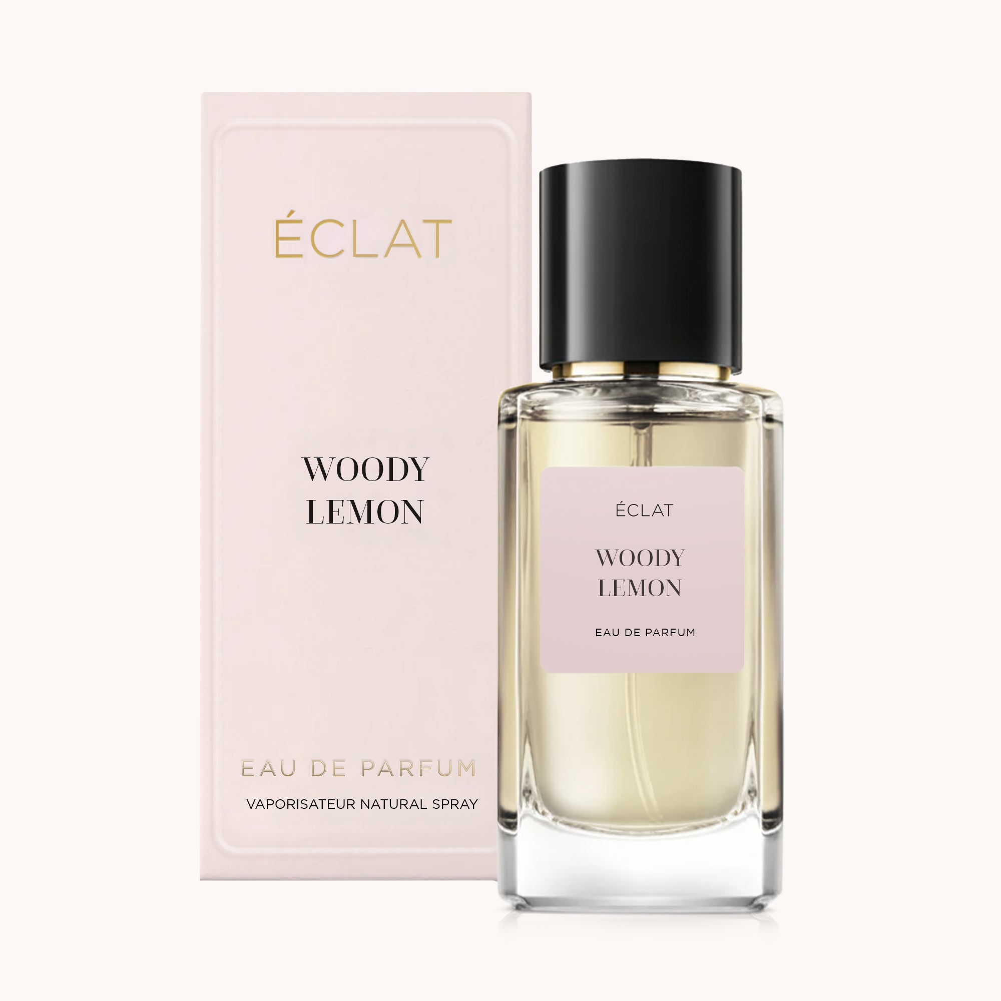 Un flacone in vetro sfaccettato di ÉCLAT Woody Lemon con tappo nero, accanto a una scatola rosa pallido con lo stesso nome.