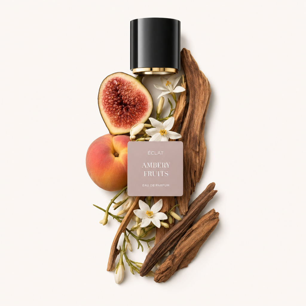 Una composizione di un fico tagliato, una pesca intera, fiori bianchi ed elementi di legno circonda l'etichetta ÉCLAT Ambery Fruits sotto un cappuccio nero con interno dorato.