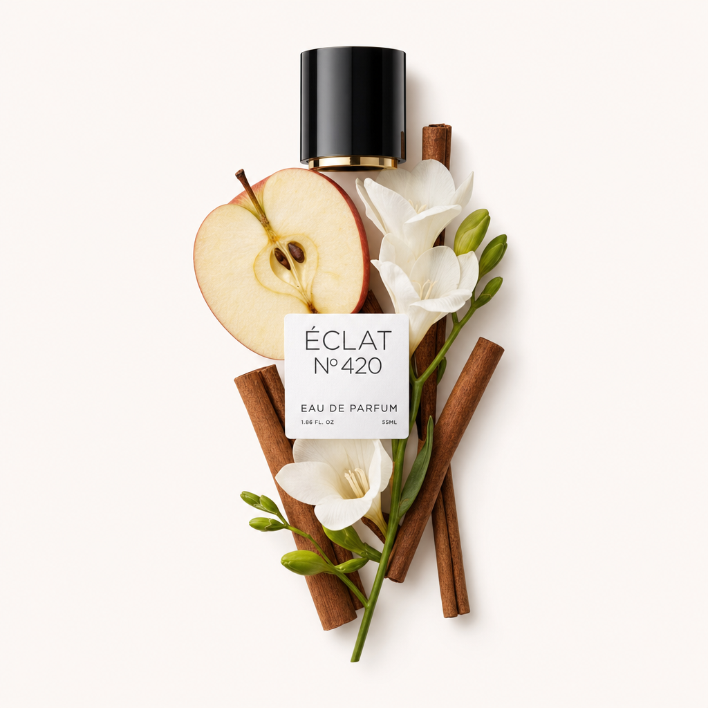 Una natura morta accuratamente disposta con fette di mela, bastoncini di cannella e fiori bianchi attorno a un tappo nero con etichetta ÉCLAT Apple & Cinnamon.