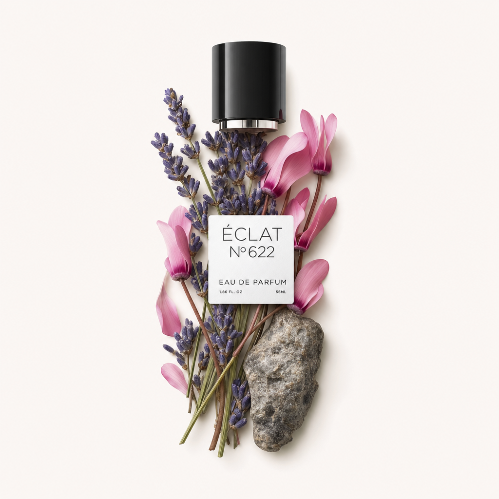 Un arrangiamento di ramoscelli di lavanda e fiori di ciclamino rosa accanto a una pietra strutturata, sormontato dal tappo nero originale di ÉCLAT con etichetta.