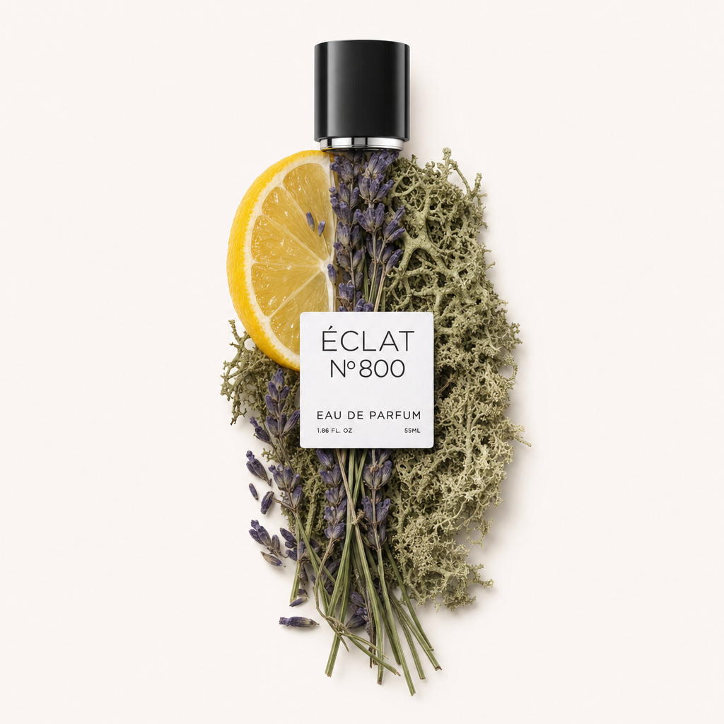Una composizione di una fetta di limone, rametti di lavanda e muschio di quercia circonda il tappo nero originale con etichetta ÉCLAT Aromatic Oak Moss.