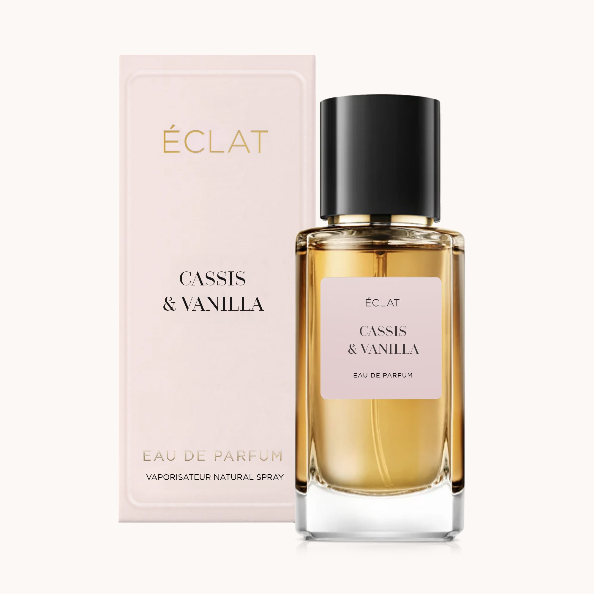 Il profumo ÉCLAT Cassis & Vanilla presenta un flacone in vetro sfaccettato con tappo nero, accompagnato da una scatola rosa pastello.