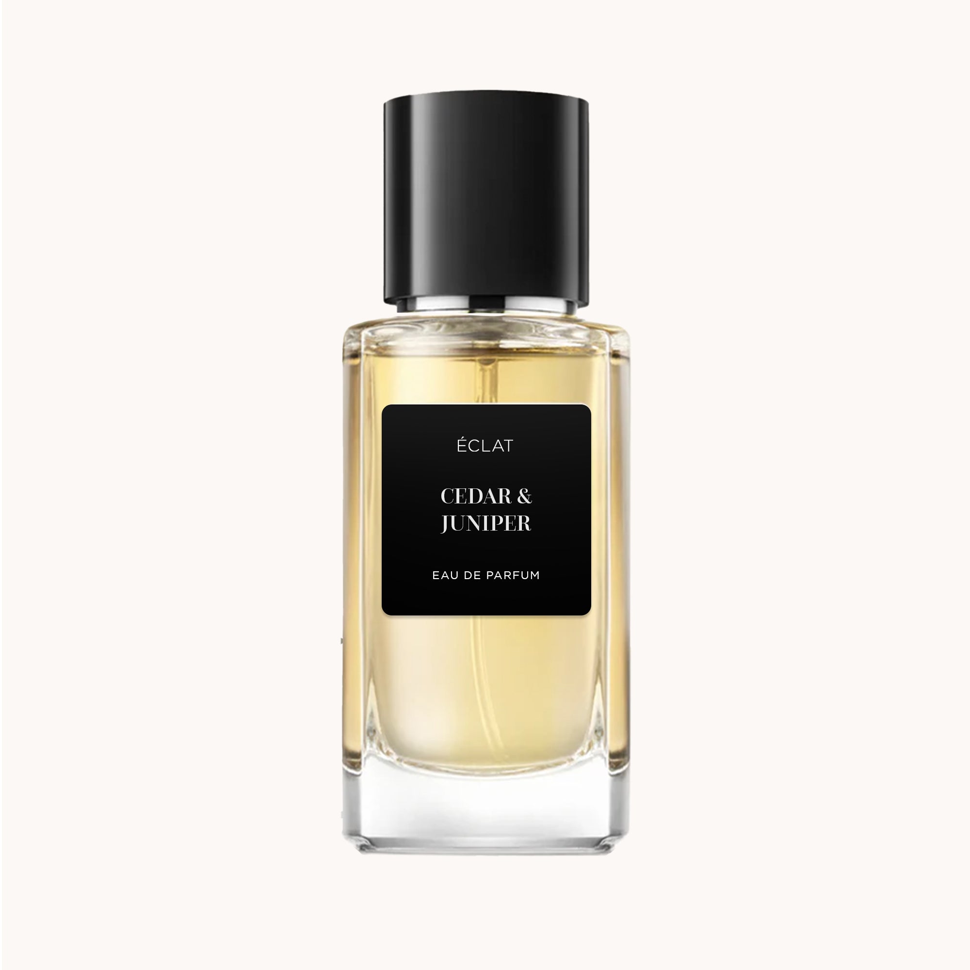 Una bottiglia di vetro sfaccettato di ÉCLAT Cedar & Juniper con tappo e etichetta neri, che mostra una fragranza dorata.