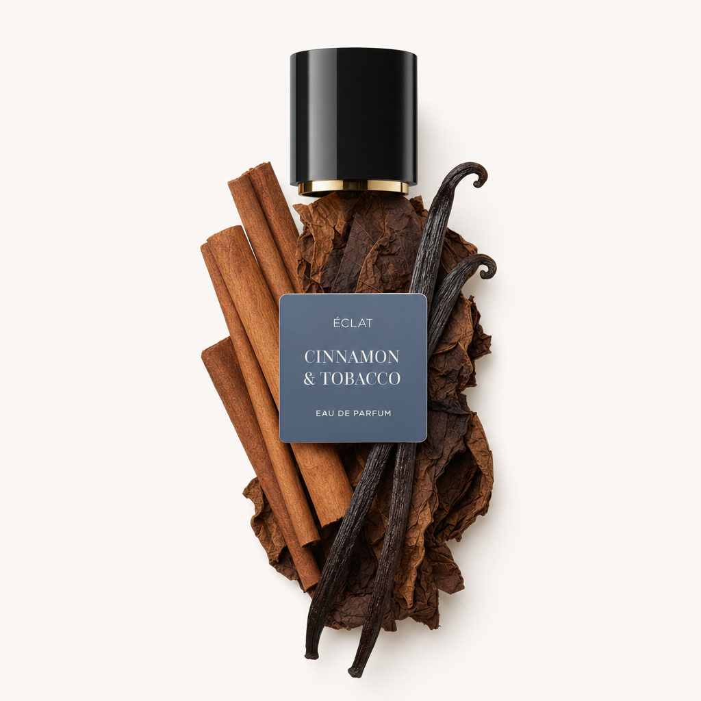 Una composizione di bastoncini di cannella, foglie di tabacco e baccelli di vaniglia circonda un tappo nero con l'etichetta ÉCLAT Cinnamon & Tobacco.