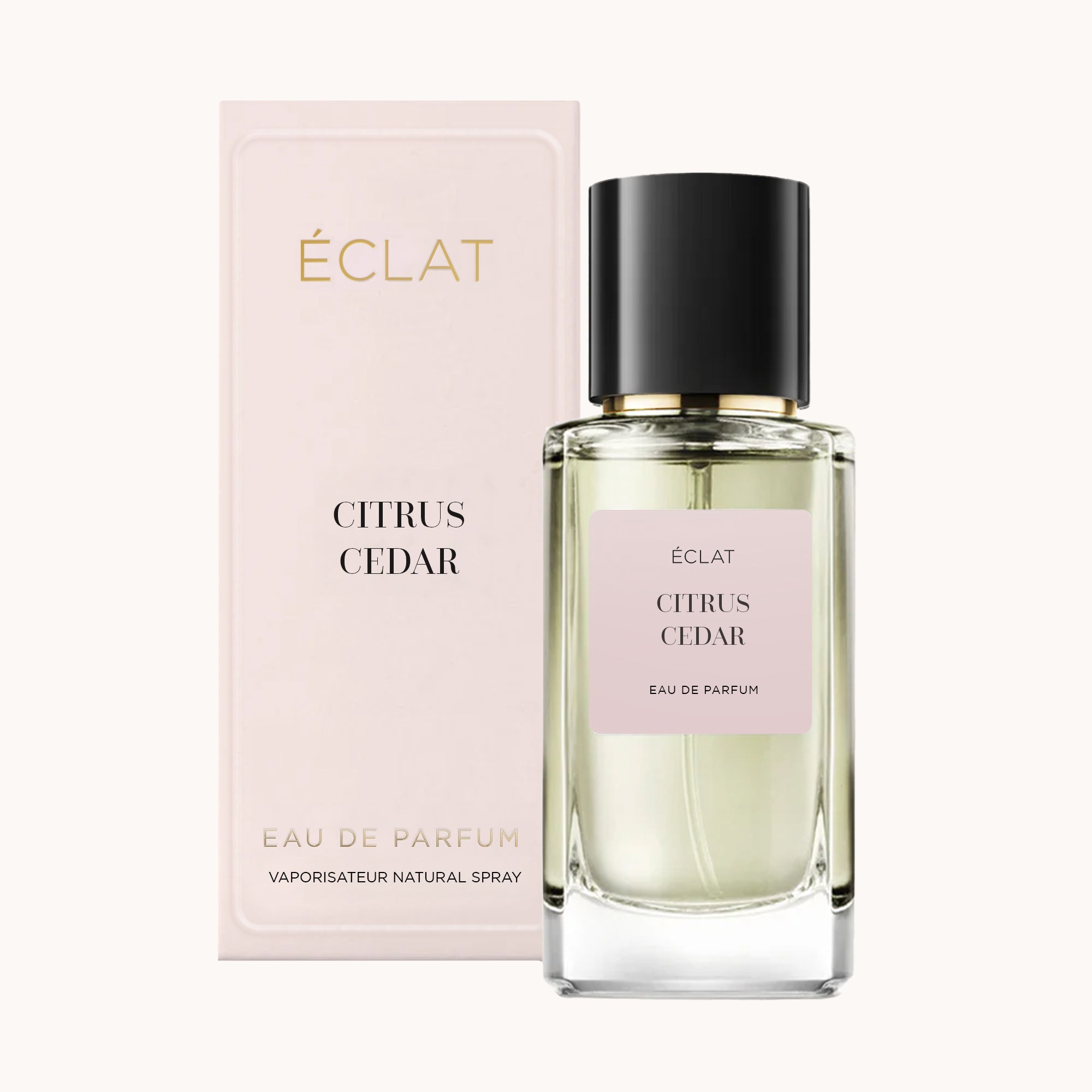 Un flacone di vetro trasparente con tappo nero e un'etichetta rosa chiaro recante 'ÉCLAT Citrus Cedar', posizionato accanto alla sua elegante scatola rosa chiaro.