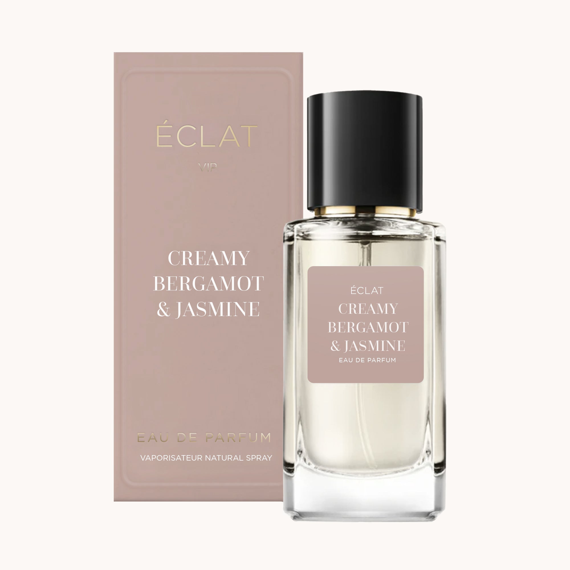Flacone di profumo ÉCLAT Creamy Bergamot & Jasmine con design sfaccettato trasparente e tappo nero, accanto a una scatola in tono rosa.