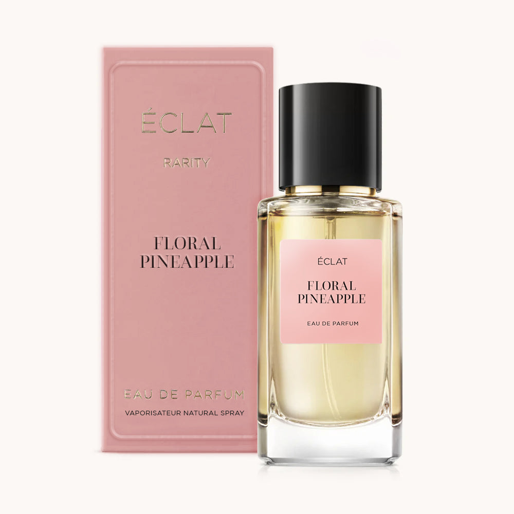 Un flacone di vetro sfaccettato ÉCLAT Floral Pineapple con tappo nero, accompagnato da una scatola rosa con lo stesso nome.