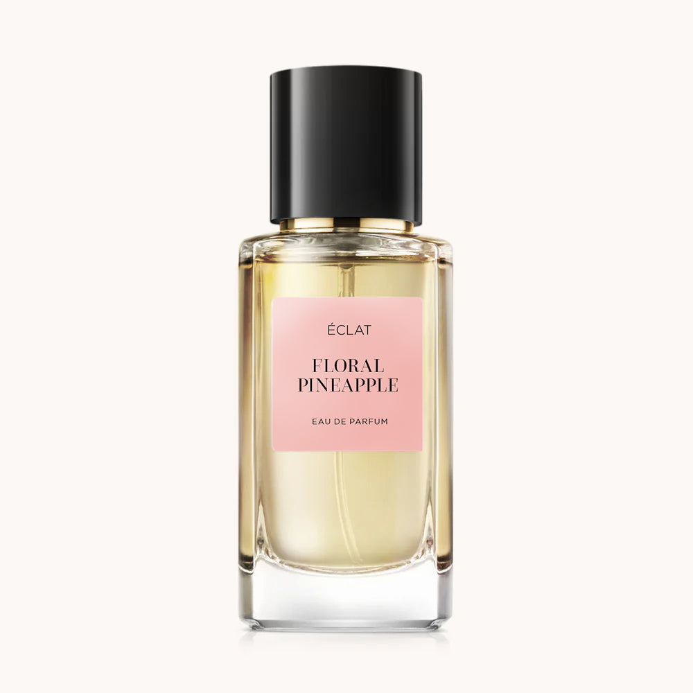 Elegante flacone in vetro di ÉCLAT Floral Pineapple con tappo nero e etichetta rosa tenue.