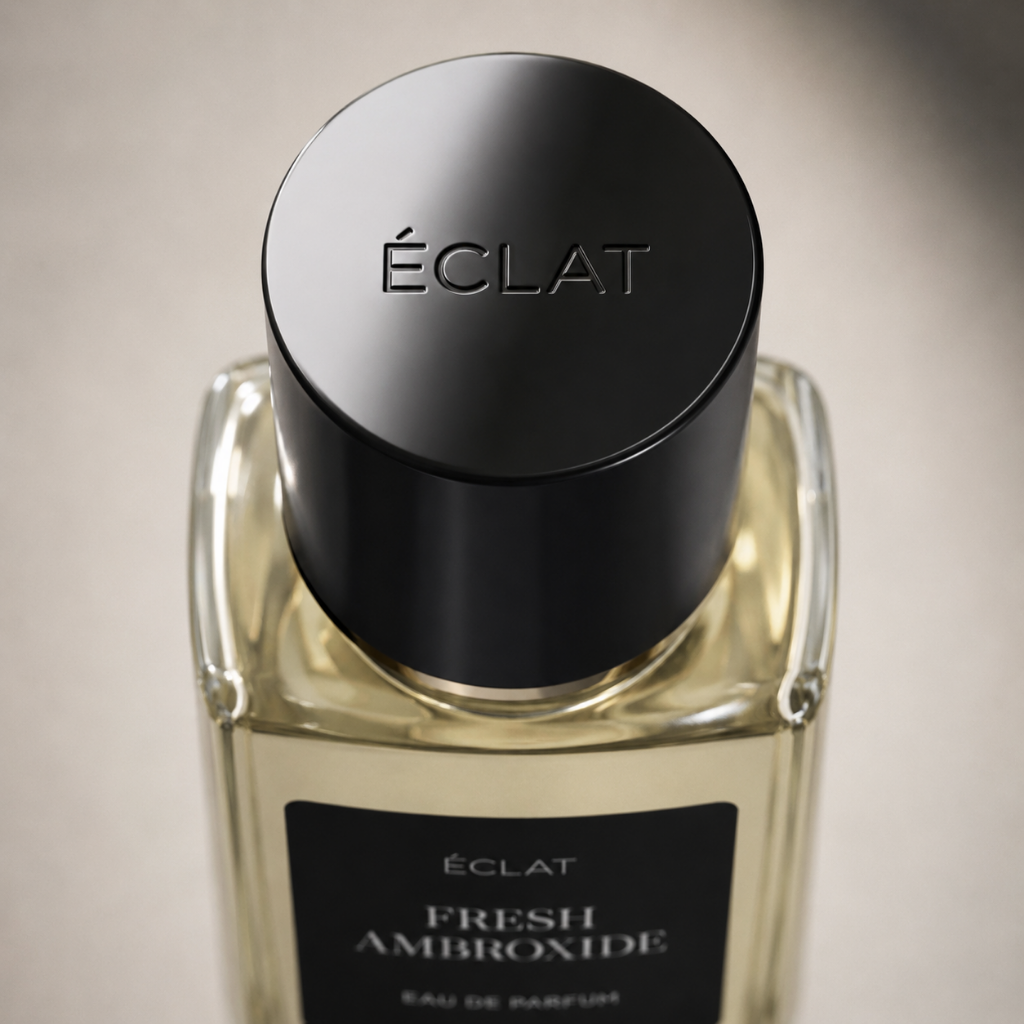Un flacone in vetro sfaccettato di ÉCLAT Fresh Ambroxide con un elegante tappo nero e un'etichetta opaca su uno sfondo neutro.