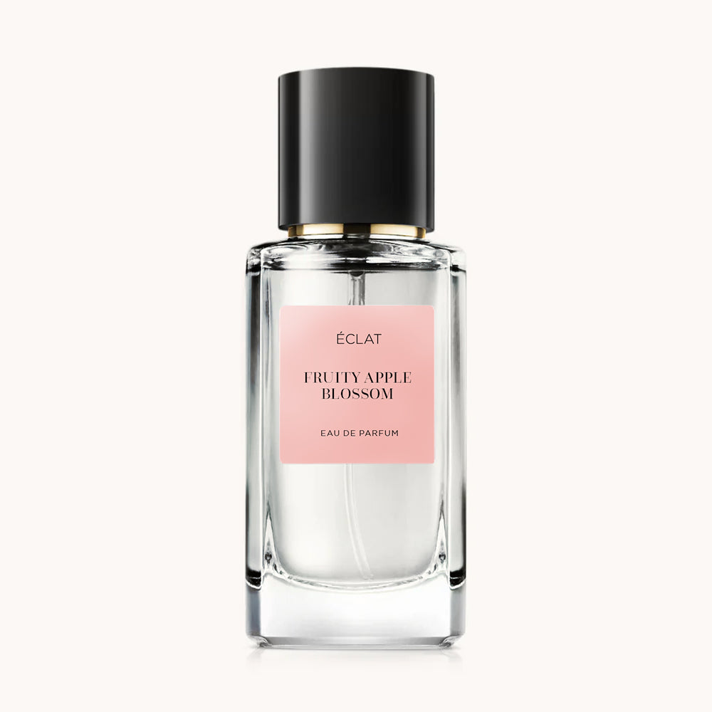 Fragranza ÉCLAT Fruity Apple Blossom in un flacone di vetro sfaccettato con tappo nero ed etichetta rosa.