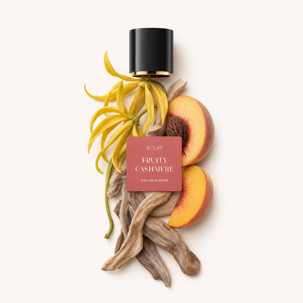 Un arrangiamento di fiori di ylang-ylang, metà pesche e bastoncini di sandalo con un tappo nero con etichetta ÉCLAT Fruity Cashmere.