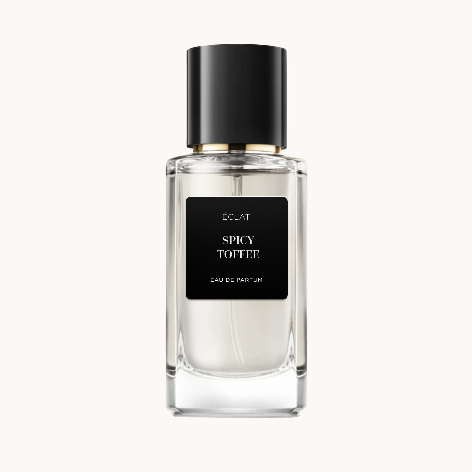 Il profumo ÉCLAT Spicy Toffee presenta un flacone in vetro sfaccettato trasparente con etichetta nera opaca e elegante tappo nero.