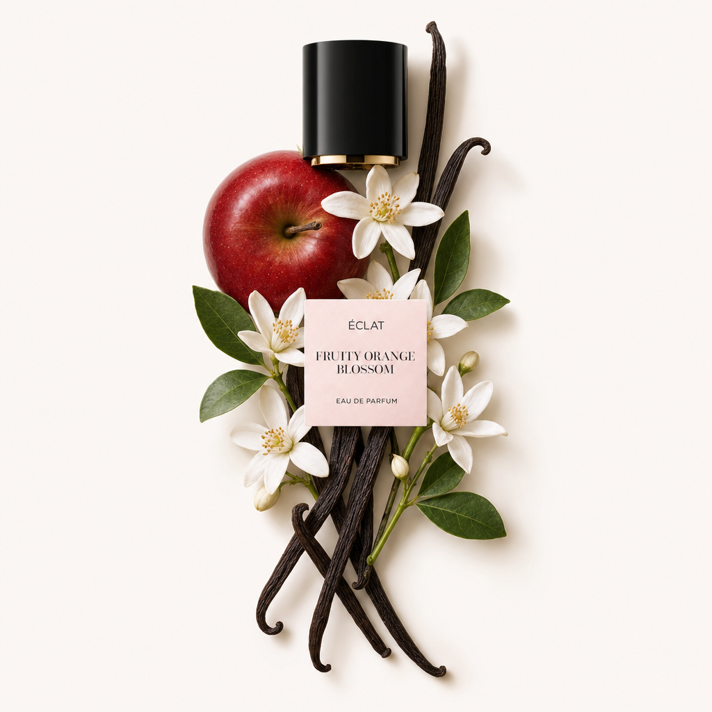 Un'artistica disposizione di una mela rossa, fiori d'arancio bianchi e baccelli di vaniglia circonda il tappo nero con l'etichetta ÉCLAT Fruity Orange Blossom.