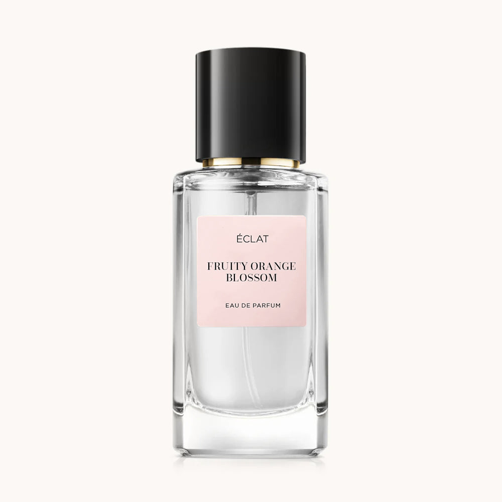 Una bottiglia di vetro sfaccettato con tappo nero e etichetta rosa per ÉCLAT Fruity Orange Blossom.