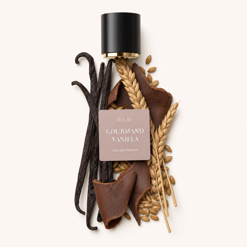 Un arrangiamento di baccelli di vaniglia, spighe di grano e pezzi di cuoio con un cappuccio nero che mostra l'etichetta ÉCLAT Gourmand Vanilla.