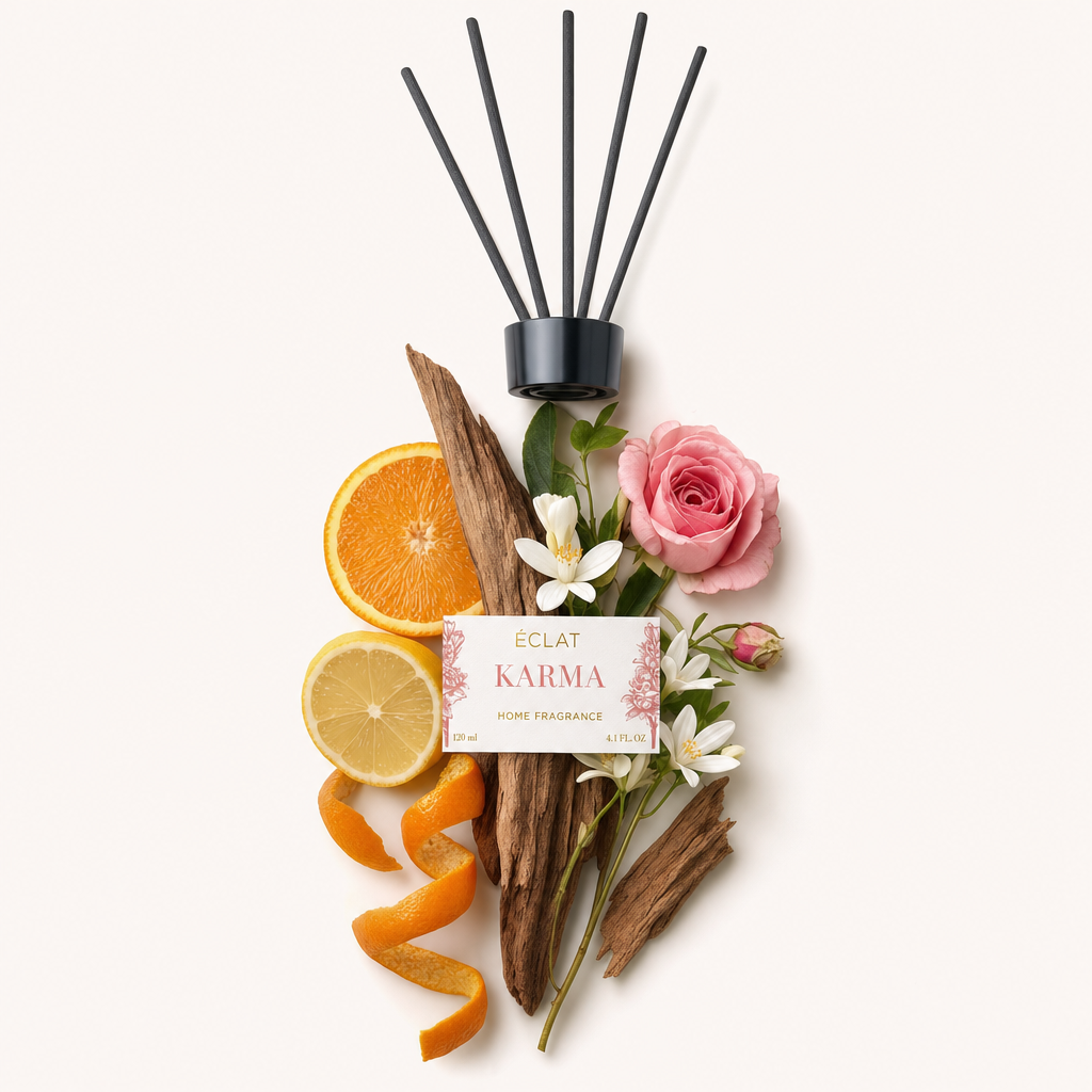 Una composizione di fette di arancia e limone, legno, fiori bianchi e una rosa rosa, sotto un tappo nero con etichetta ÉCLAT Karma.