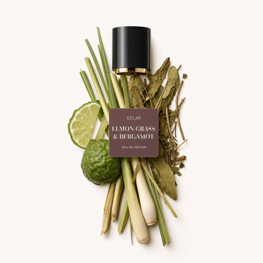 Un arrangiamento di steli di lemongrass, foglie di lime kaffir, fette di lime e frutto di bergamotto intero, accanto a un tappo nero con etichetta ÉCLAT Lemon Grass & Bergamot.