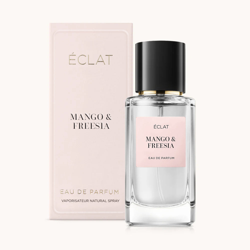 Profumo ÉCLAT Mango & Freesia in un flacone di vetro trasparente con tappo nero, accompagnato da una confezione rosa tenue.