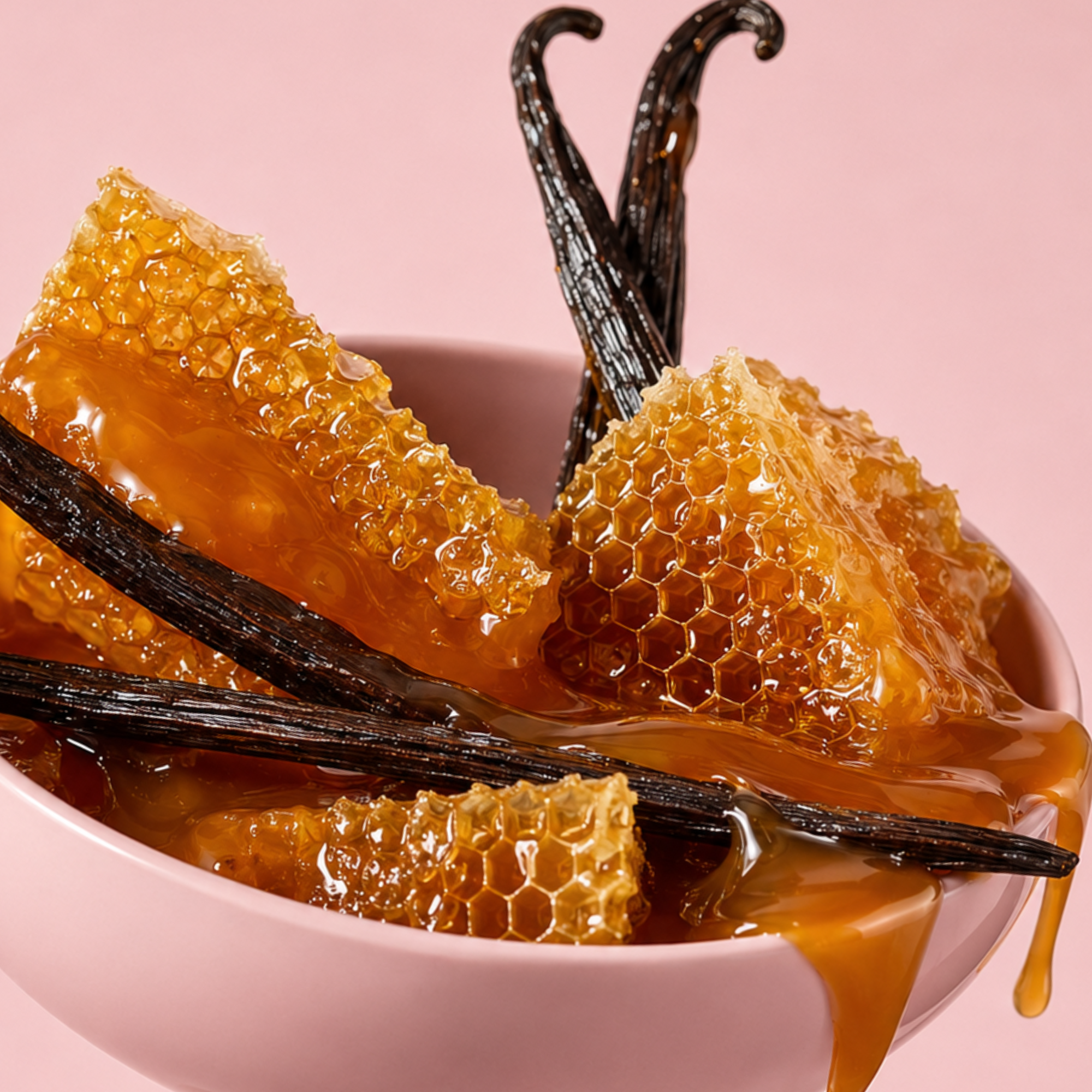 Pezzi di favo al miele con caramello e baccelli di vaniglia in una ciotola in ceramica rosa su uno sfondo rosa tenue.