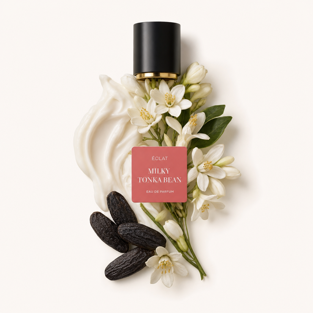 Una composizione di vortici cremosi, fagioli tonka e delicati fiori bianchi, con un tappo nero etichettato ÉCLAT Milky Tonka Bean.