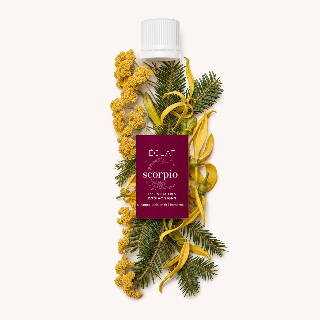 Un arrangiamento di fiori di ylang-ylang gialli, fiori di immortelle gialli e rami di abete verde circonda un tappo nero con etichetta degli oli essenziali Zodiac Sign Scorpio di ÉCLAT.