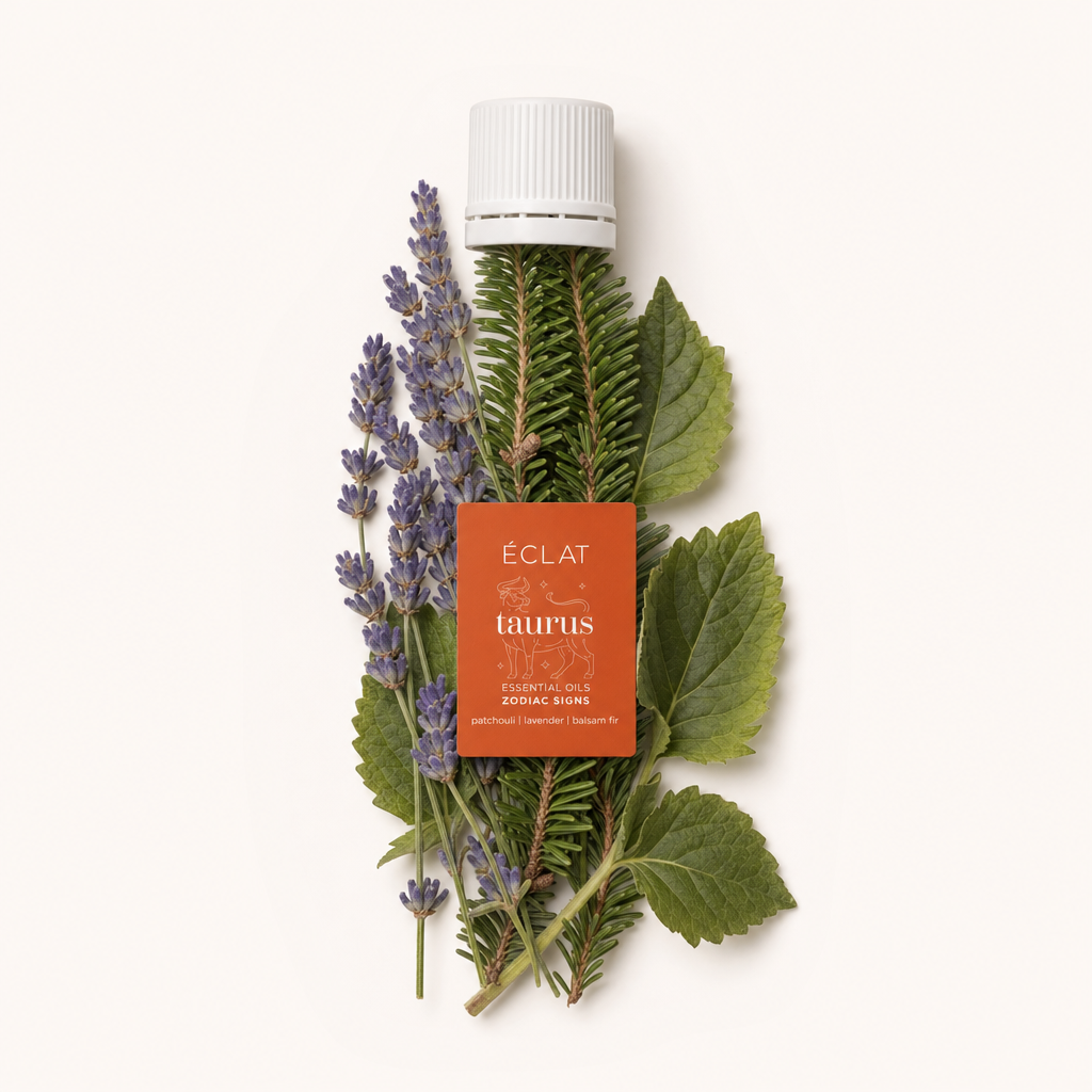 Un arrangiamento di rametti di lavanda, rami di abete balsamico e foglie di patchouli circonda un tappo nero con etichetta arancione ÉCLAT Taurus.