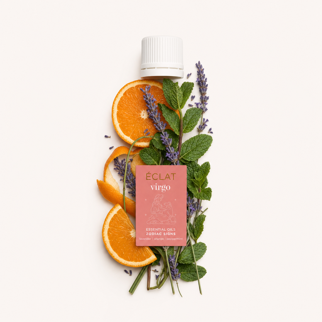 Una composizione armoniosa di ramoscelli di lavanda, fette d'arancia e foglie di menta verde circonda un tappo nero con etichetta ÉCLAT Virgo.