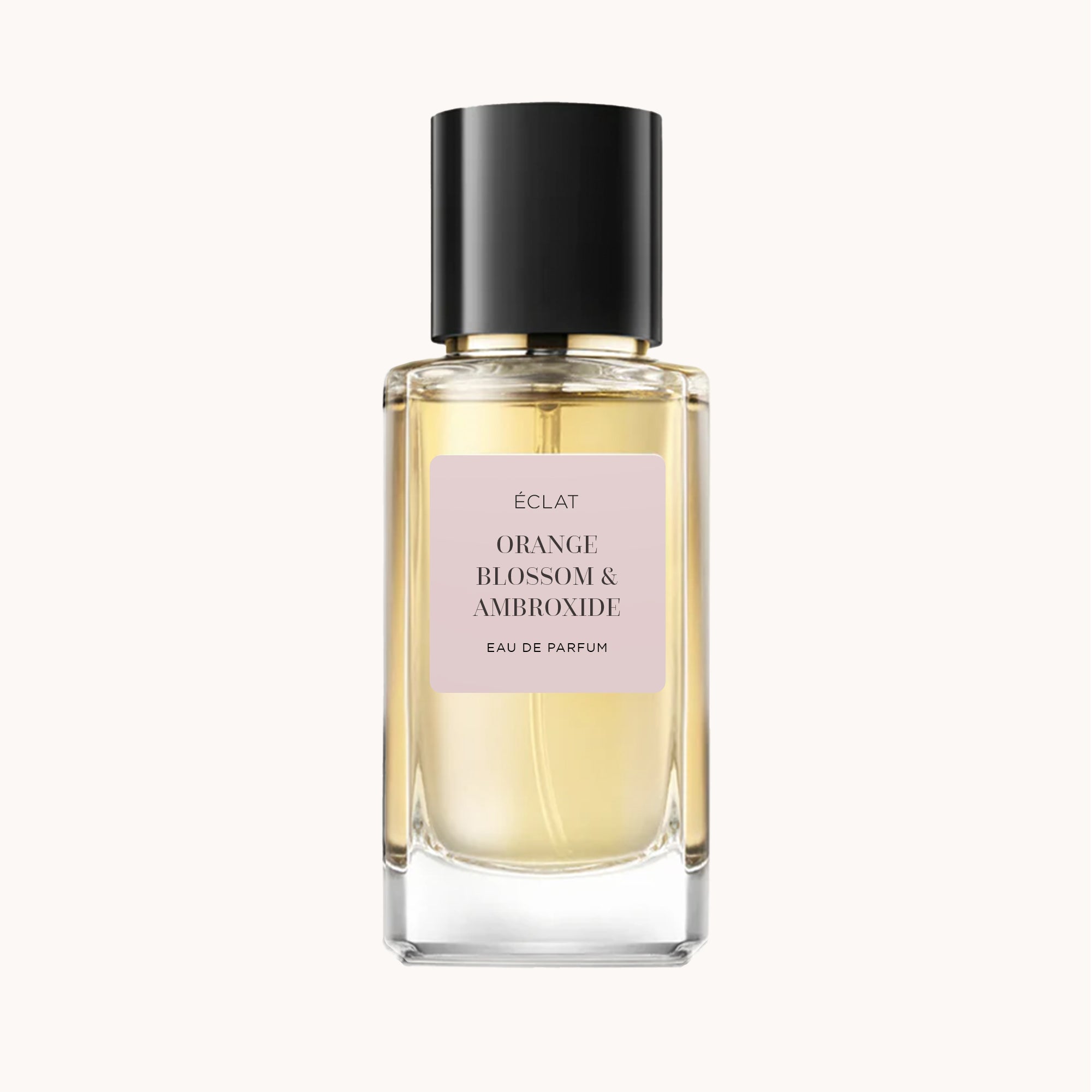 Bottiglia in vetro sfaccettato di ÉCLAT Orange Blossom & Ambroxide con tappo nero e etichetta rosa tenue.