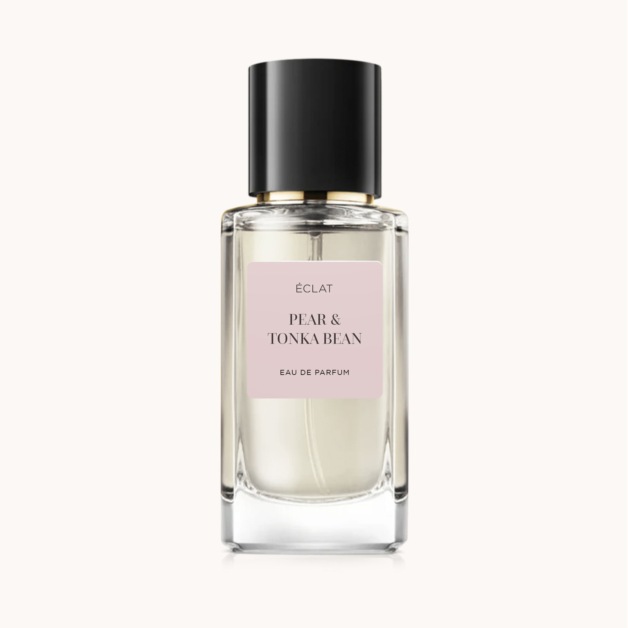 Flacone in vetro trasparente di ÉCLAT Pear & Tonka Bean con tappo nero ed etichetta rosa pallido sul fronte.