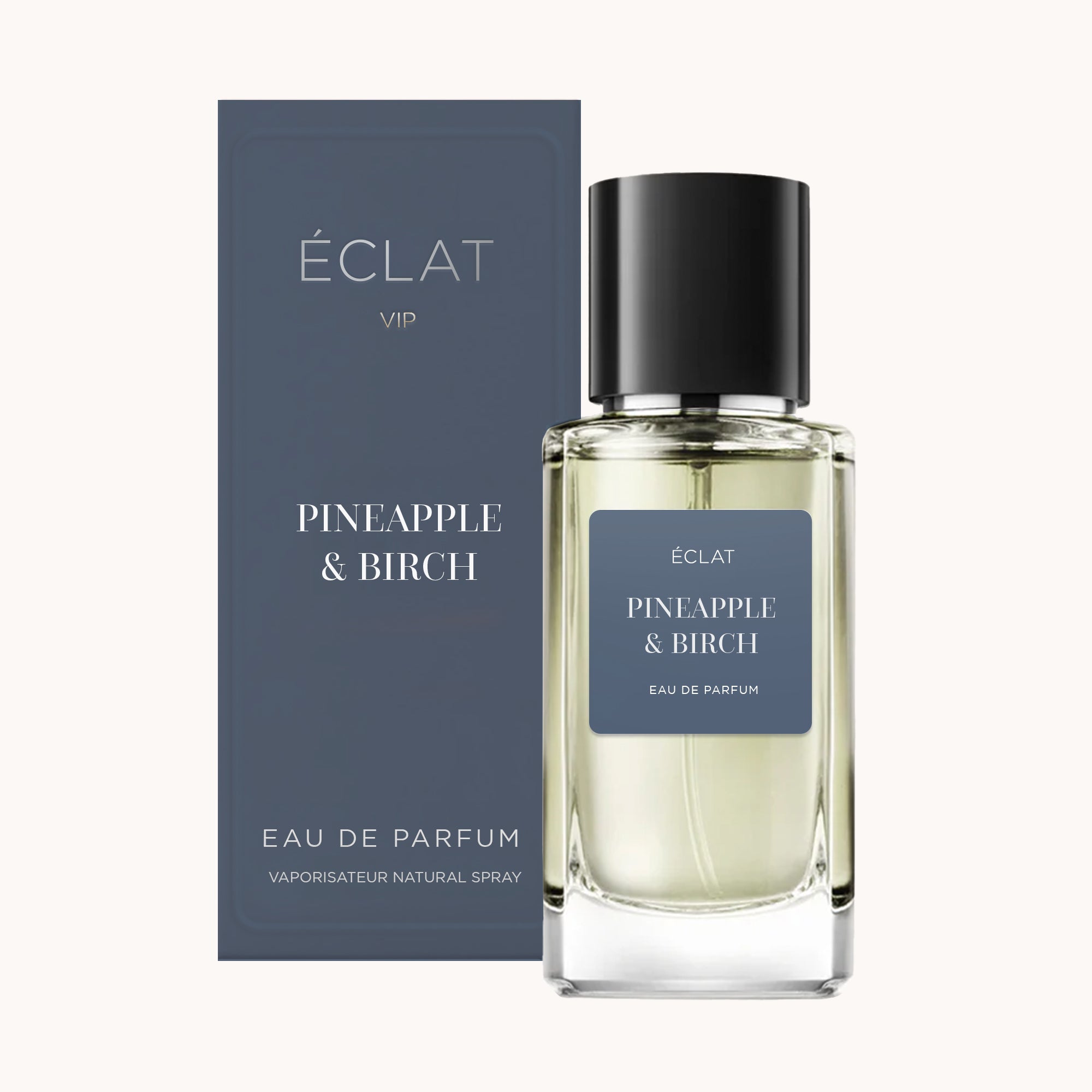 Profumo ÉCLAT Pineapple & Birch in un flacone di vetro trasparente con tappo nero, accanto a una scatola blu scuro abbinata.