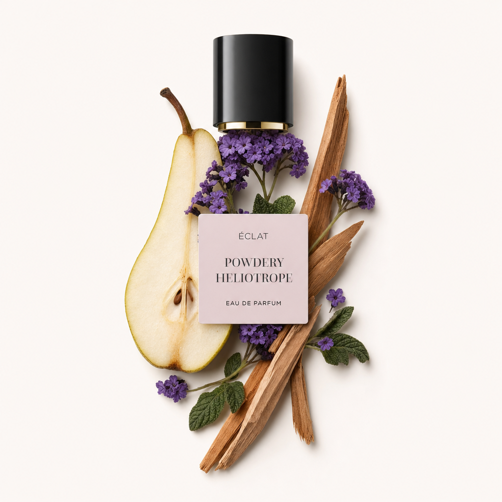 Una composizione di fiori di eliotropio viola, una pera affettata, foglie verdi e bastoncini di legno circonda un tappo nero con etichetta per ÉCLAT Powdery Heliotrope.