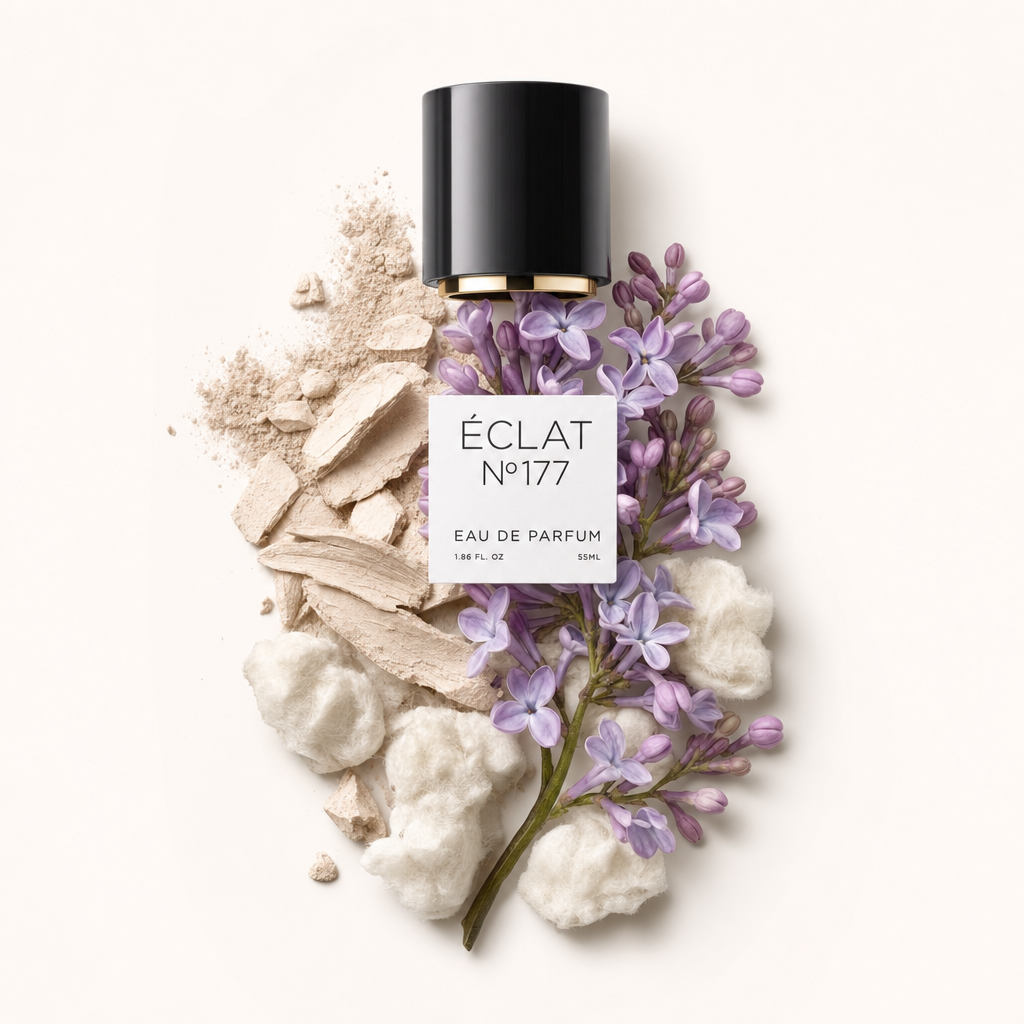 Una composizione di fiori di lillà dai delicati toni viola, circondata da soffice cotone bianco e frammenti di polvere beige. In alto si trova un tappo nero con bordo dorato ed etichetta ÉCLAT.
