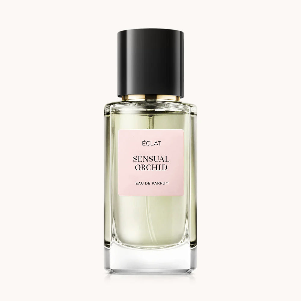 Profumo ÉCLAT Sensual Orchid in una bottiglia di vetro trasparente sfaccettato con tappo nero e etichetta rosa tenue.