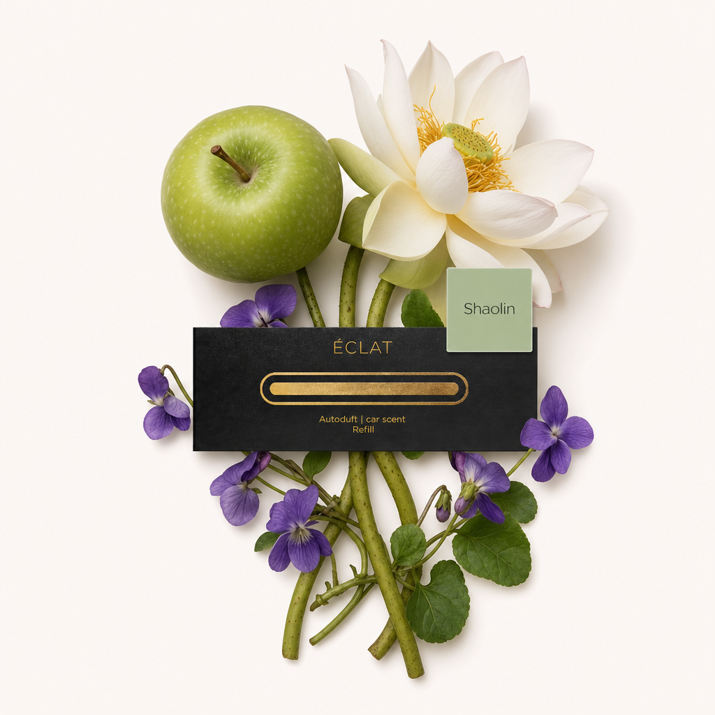 Un arrangiamento di mela verde, fiore di loto bianco e violette viola circonda un tappo nero ÉCLAT con etichetta 'Shaolin'.