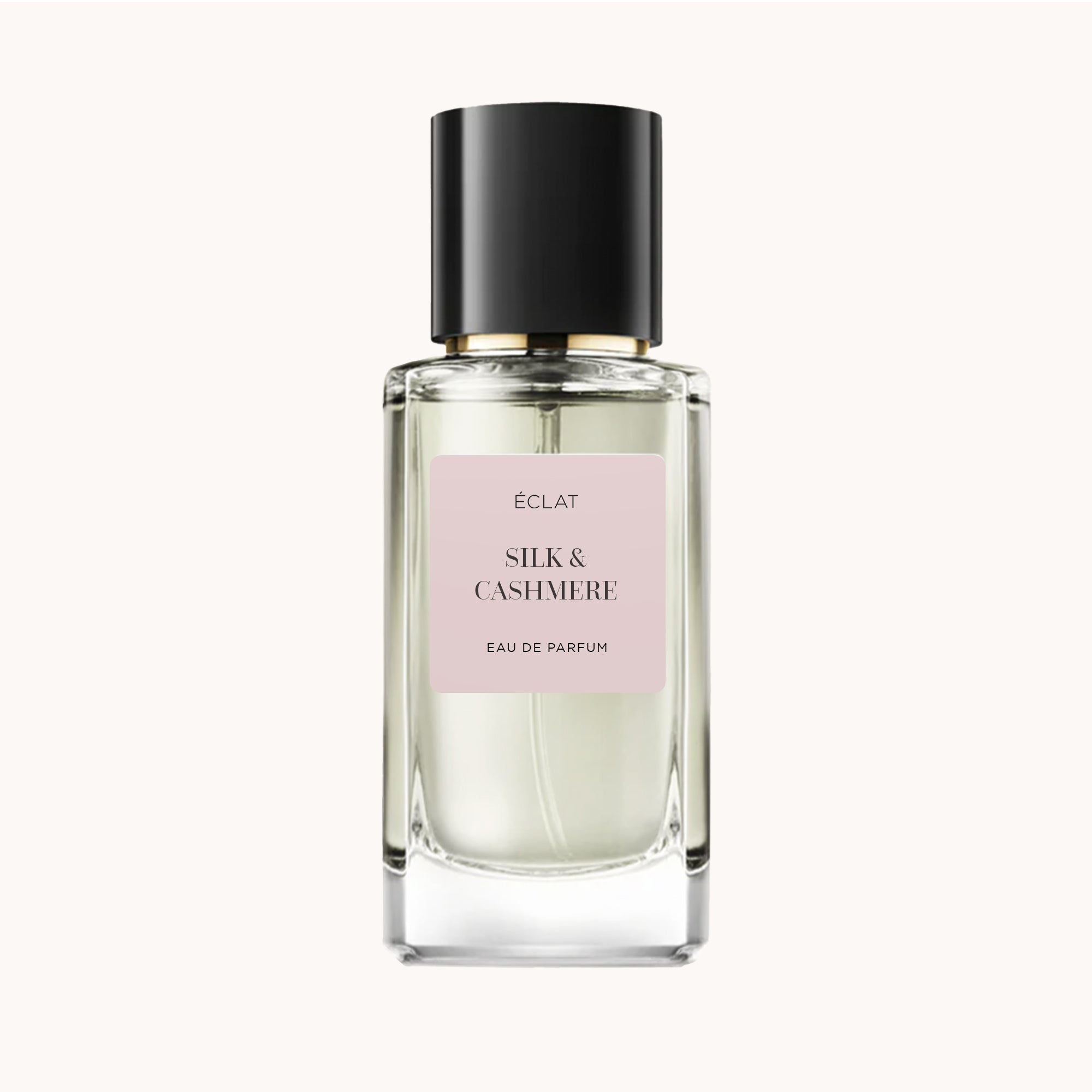 Flacone in vetro sfaccettato con tappo nero opaco ed etichetta rosa chiaro con ÉCLAT Silk & Cashmere.